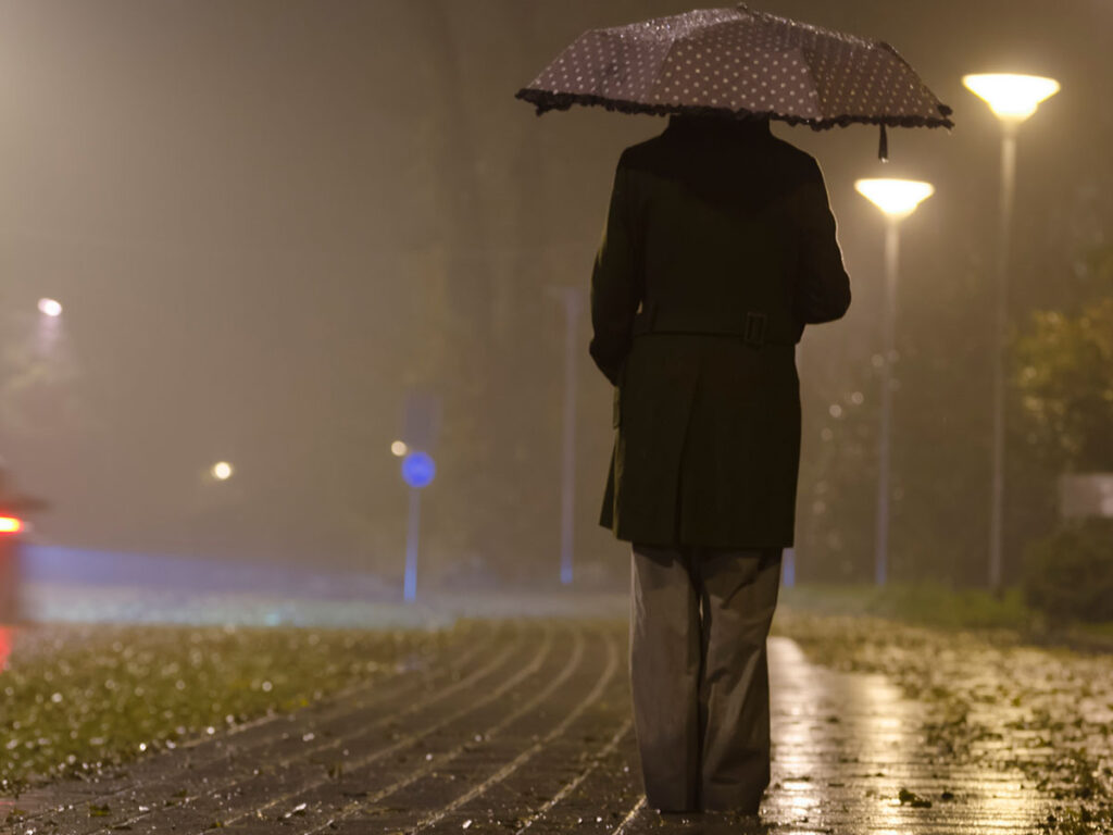 Femme sous un parapluie, nuit brumeuse.