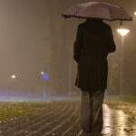 Femme sous un parapluie, nuit brumeuse.