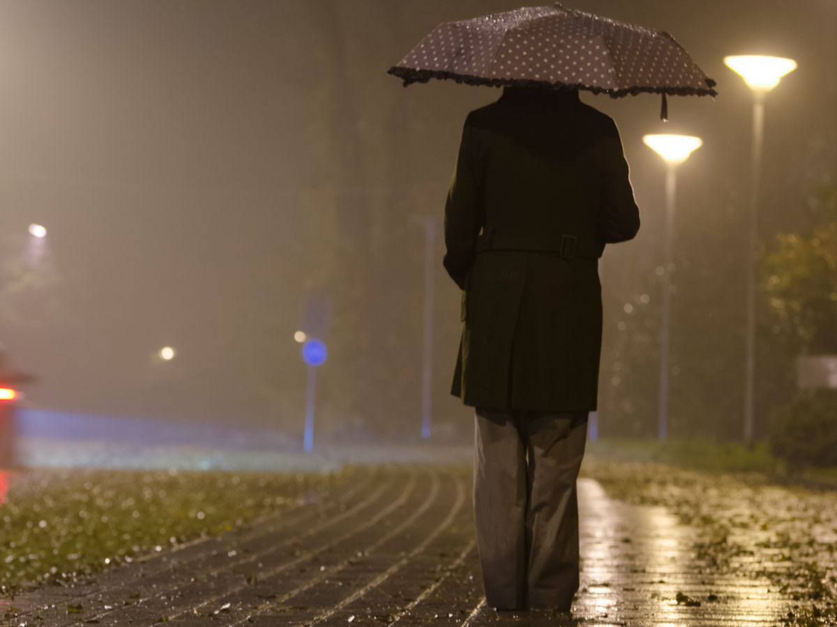 Femme sous un parapluie, nuit brumeuse.